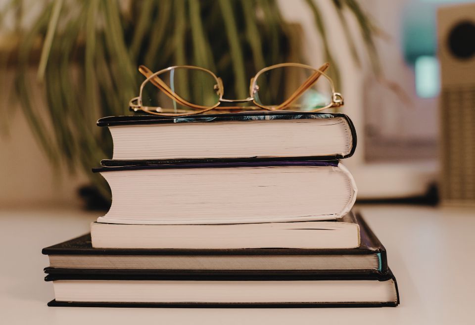 Pile de livres avec des lunettes posées dessus, symbolisant la recherche académique et la liberté de pensée dans le cadre de l'appel à contributions sur la liberté académique dans les démocraties européennes et nord-américaines.