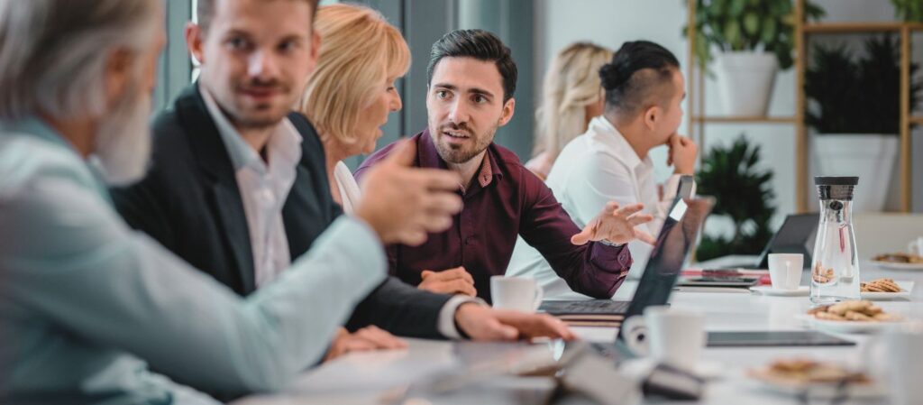 Un groupe de professeur·es universitaires discutant autour d’une table, illustrant la collaboration et la collégialité au cœur de la gouvernance académique. L’image reflète un échange constructif entre pairs, essentiel à la gestion participative et à l’autonomie des universités.