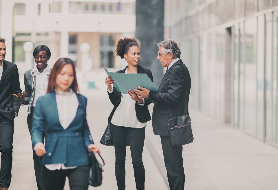 Un groupe de professeur·es universitaires en discussion à l'extérieur d'un campus. Cette image illustre la collaboration et l'échange d'idées, des principes essentiels à la collégialité et à la gouvernance participative dans les universités.