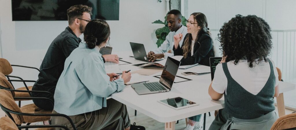 Un groupe de professeur·es universitaires collaborant autour d’une table en réunion. Cette image illustre la participation active et l’échange d’idées, essentiels pour renforcer la collégialité et la gouvernance participative dans les universités.