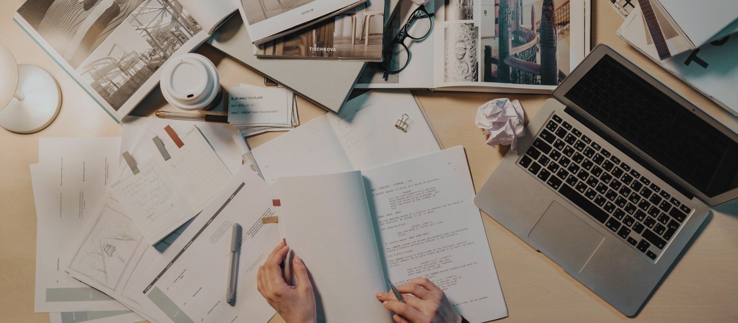 Bureau de travail de chercheur·euse avec documents, manuscrits, ordinateur portable, café et livres ouverts, illustrant la recherche universitaire et les défis liés au financement de la recherche au Québec.