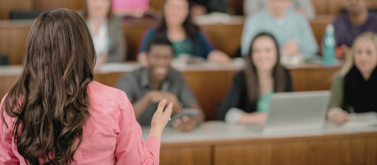 Une professeure s’adressant à une classe universitaire, illustrant les luttes féministes pour l’égalité des femmes dans l’enseignement supérieur. Cette image met en avant la nécessité d’une représentation accrue des femmes dans les universités et les postes de leadership académique.