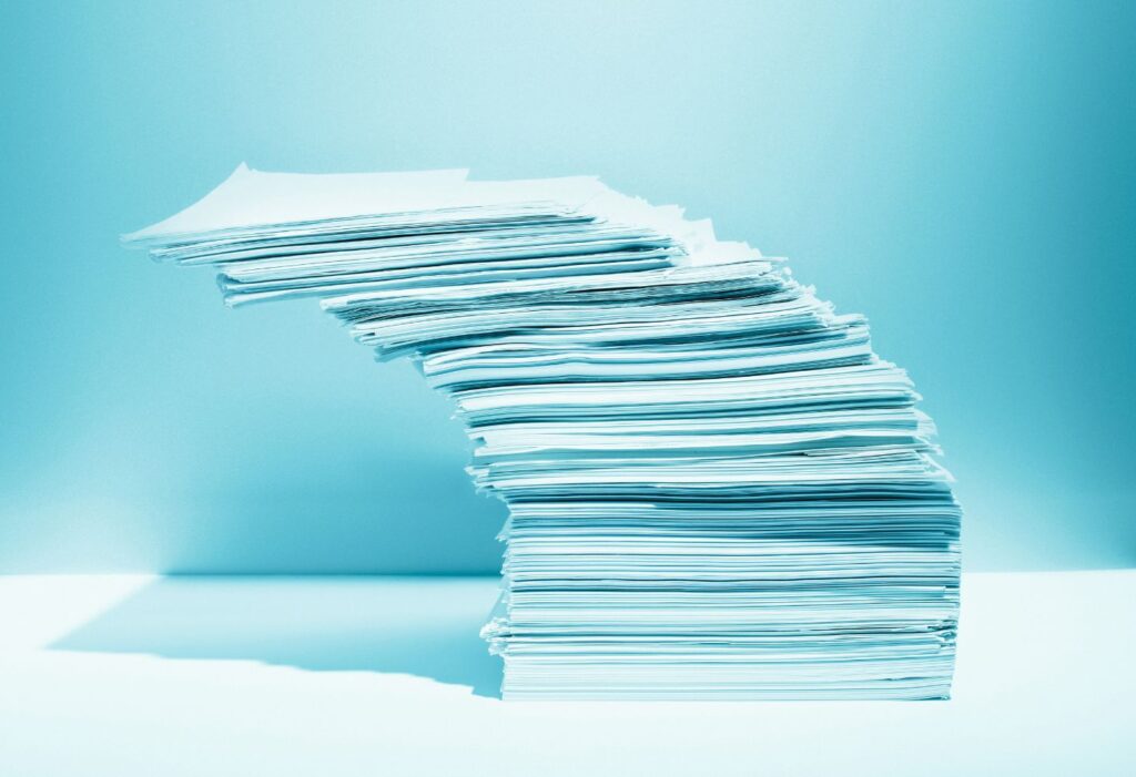 Une pile de documents penchée illustrant la précarité dans le milieu universitaire, en lien avec les enjeux de liberté académique soulevés par le COPLA.