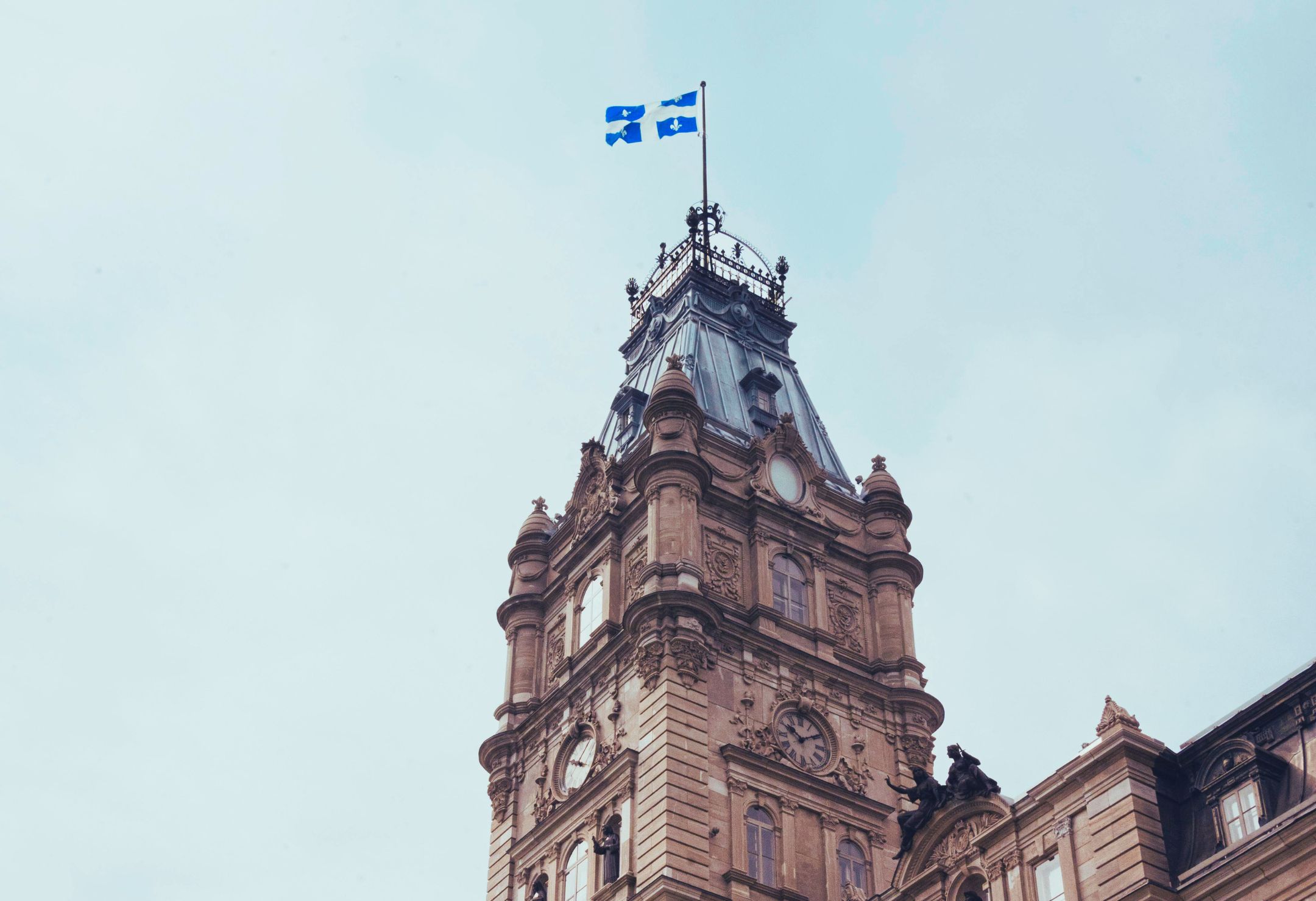 Façade de l’Assemblée nationale du Québec surmontée du drapeau québécois, illustrant le débat entourant le projet de loi 7 et ses impacts sur la liberté académique.