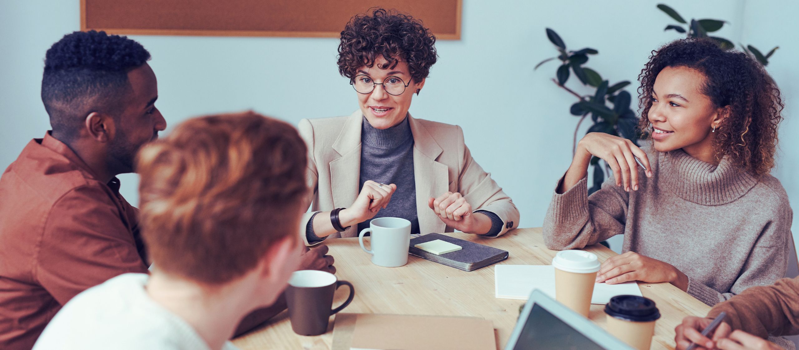 Groupe de personnes en discussion autour d’une table, illustrant collégialité universitaire en milieu universitaire.