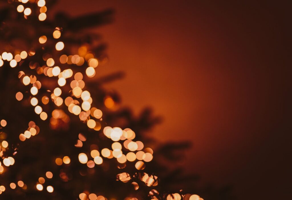 Guirlandes lumineuses floues sur un sapin, créant une ambiance chaleureuse de fin d’année.