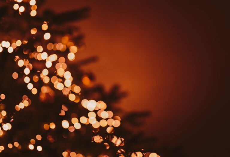 Guirlandes lumineuses floues sur un sapin, créant une ambiance chaleureuse de fin d’année.
