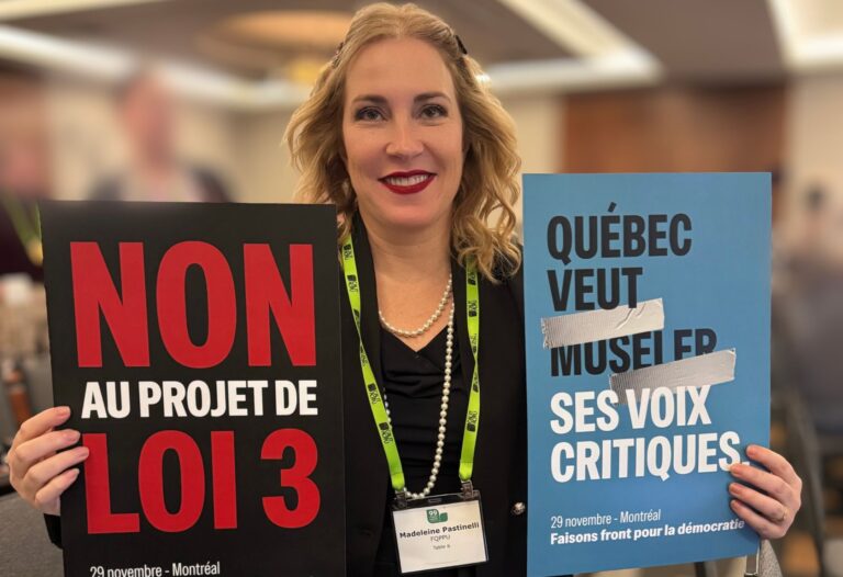 Madeleine Pastinelli tenant deux pancartes contre le projet de loi 3 lors de l’Assemblée du Conseil de l’ACPPU, le 29 novembre 2025.