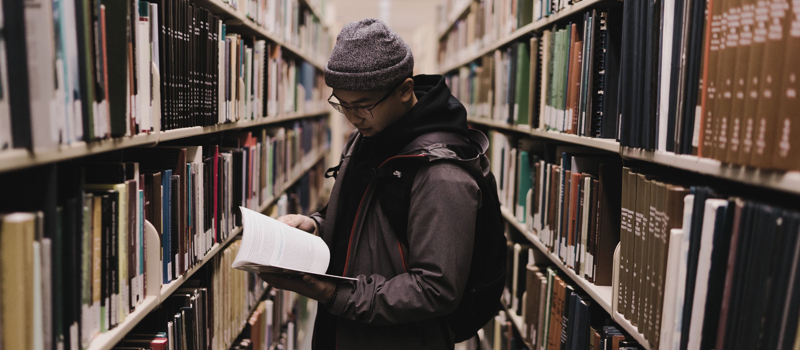Étudiant lisant dans une bibliothèque universitaire au Québec dans un contexte de transformation de l’enseignement supérieur