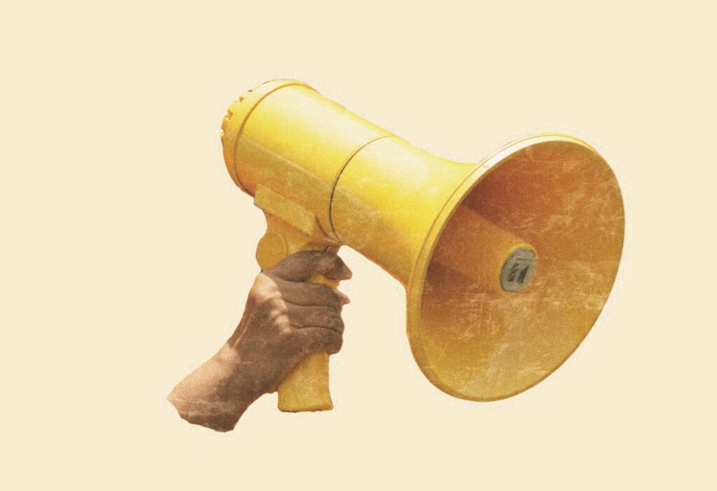 Main tenant un mégaphone jaune pour défendre la liberté académique et la négociation collective