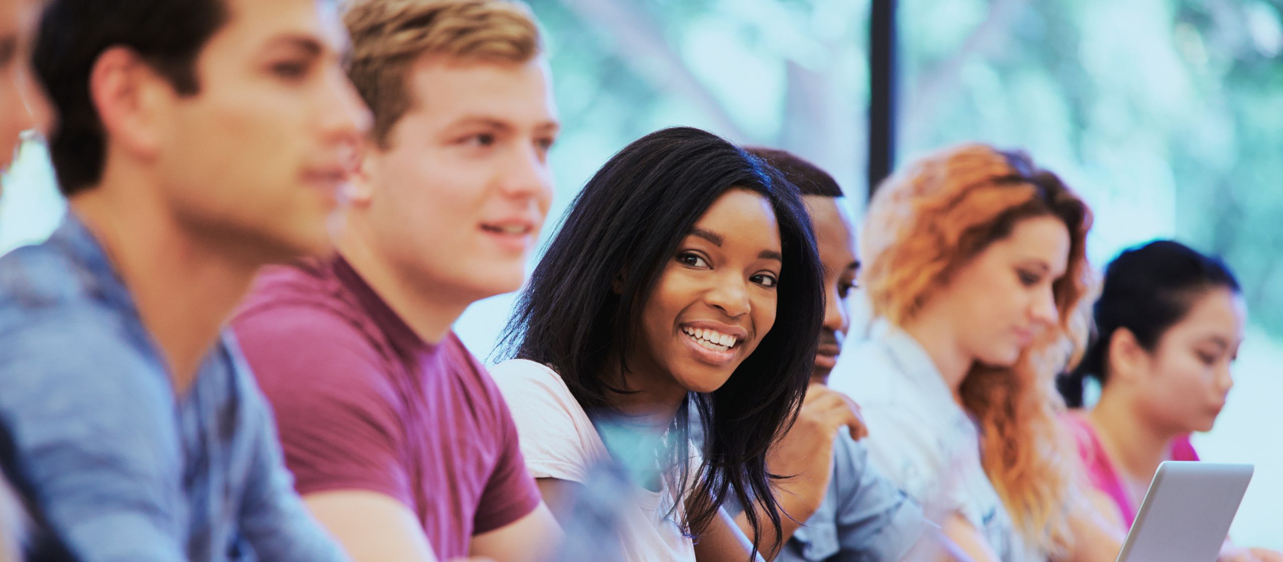 Groupe d’étudiant·es en contexte d’enseignement universitaire, assis côte à côte en classe et participant à une activité d’apprentissage.