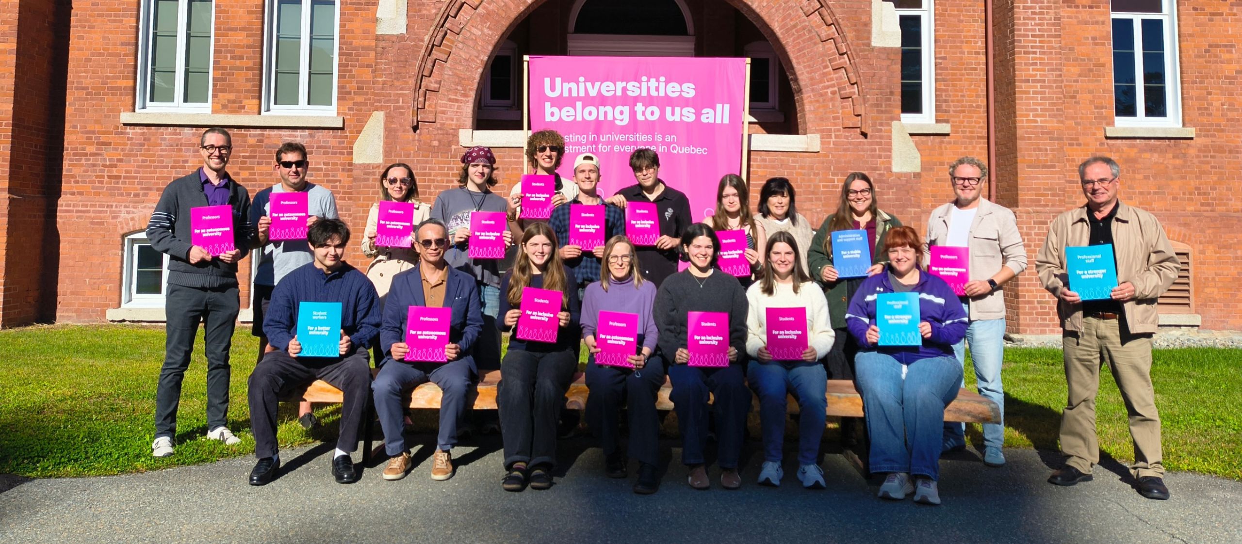 Des membres d’une communauté universitaire réunis avec des affiches réclamant une université inclusive et accessible.