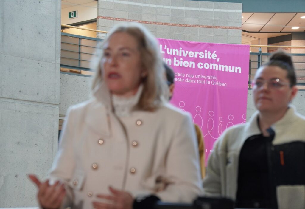Mobilisation pour le financement des universités au Québec devant une affiche « L’université, un bien commun ».